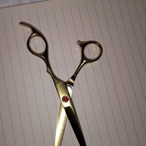 Tijera de corte dorada con estras rojo